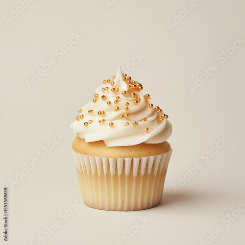 A single vanilla cupcake with gold sprinkles on a neutral background