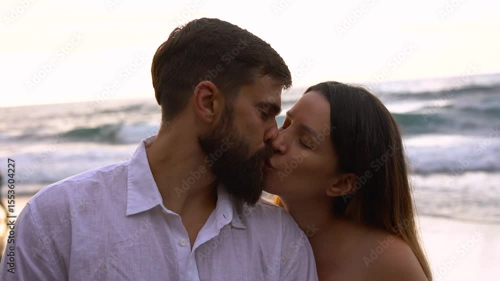 Happy young couple kissing each other on the beach during summer vacation - Travel, holiday and relationship concept Happy young couple kissing each other on the beach during summer vacation - Travel, holiday and relationship concept