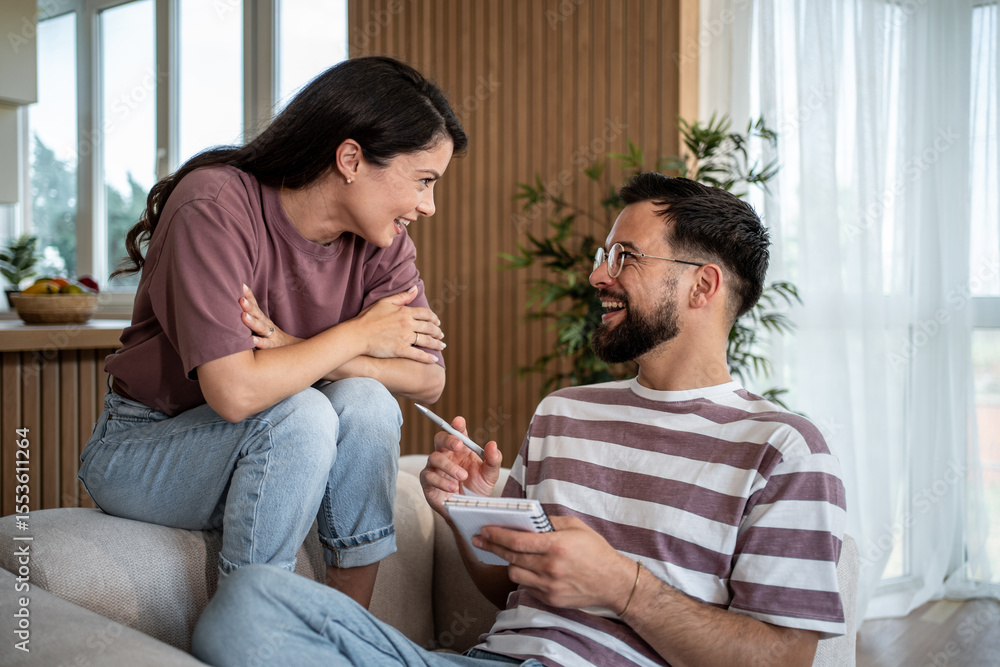 Fototapeta premium Couple planning future, taking notes and smiling at home