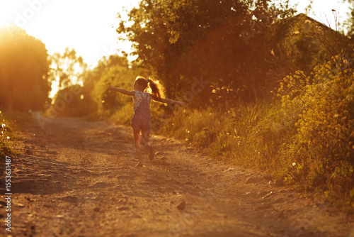 Happy girl runs along a country road.