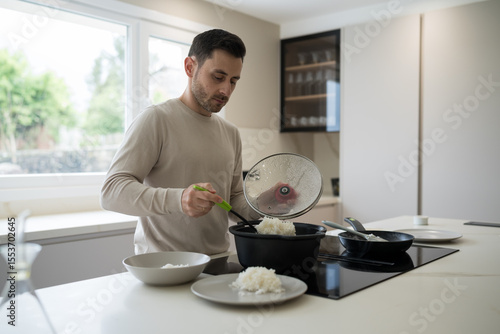Obraz na plátně Man serving rice in modern kitchen, cooking and nutrition