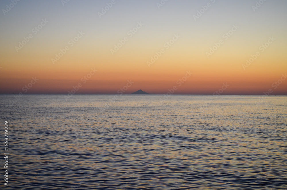 Fototapeta premium The ocean is calm and the sky is a beautiful orange color. The sun is setting, creating a warm and peaceful atmosphere