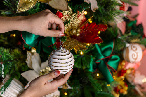 Woman Hanging White Christmas Ornament on Decorated Tree
