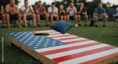 Group of people playing outdoor cornhole with American flag painted wooden board on green lawn