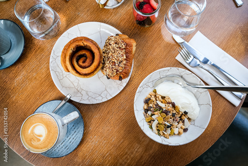 Continental breakfast on a table. Simple choice of pastries, yoghurt, cereals, toast with jam and butter, fruits. With coffees and juices. Breakfast for two at the table