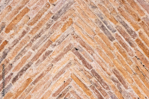 Background of old bricks laid in a herringbone pattern on a vault of a 17th century building
