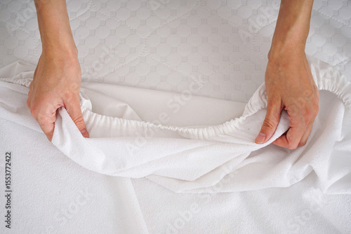 Young woman?s hands putting fitted sheet on baby crib mattress.