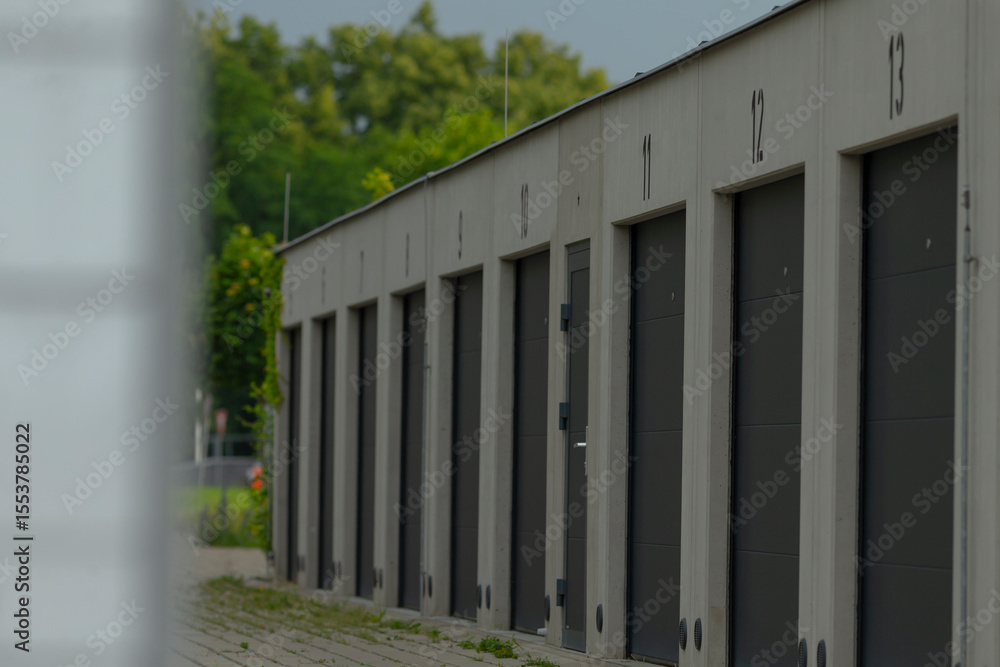 A long row of gray buildings stands tall, each featuring black doors with numbers clearly displayed on them for easy identification A long row of gray buildings stands tall, each featuring black doors with numbers clearly displayed on them for easy identification