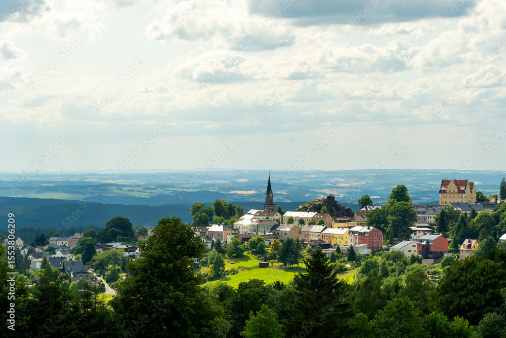 Fototapeta premium Charming hilltop village with lush greenery and rolling hills during a sunny afternoon in summer