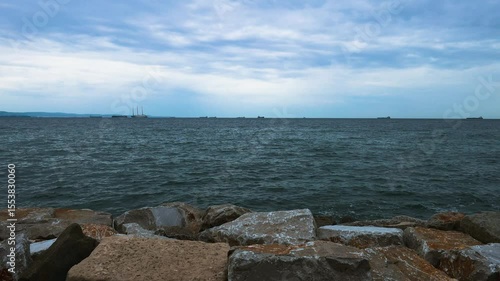 Rocky Embankment with Ships in the Distance, Waves Crashing on Rocks