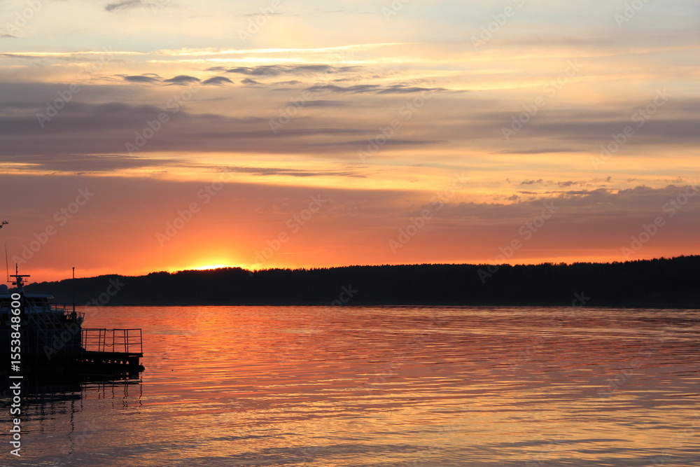 Tranquil Sunset Over Calm Water with Vibrant Orange and Purple Sky Reflections and Dock Extending Toward Tree-Lined Horizon Tranquil Sunset Over Calm Water with Vibrant Orange and Purple Sky Reflections and Dock Extending Toward Tree-Lined Horizon