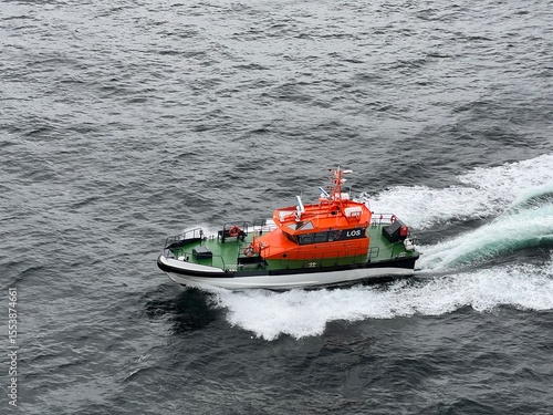 orange pilot boat alongside ship