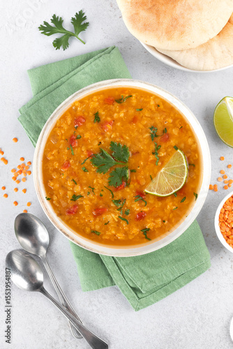 Traditional Indian dal soup with red lentils, spices, fresh cilantro and lime on a white background. Indian food