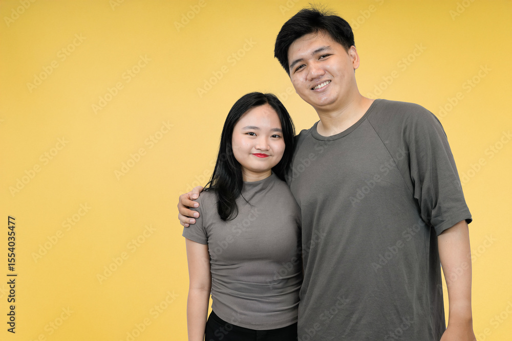 Fototapeta premium happy young asian couple smiling in yellow background studio