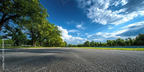 Asphalt road vanishing into a summer landscape under a vibrant blue sky