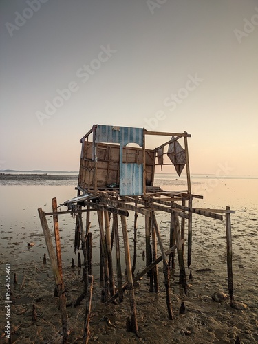 Dilapidated stilt house remains at low tide, showcasing the wear of time and coastal erosion.