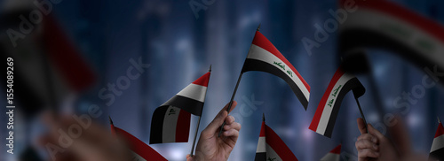 Iraq flags in their hands on a blurred urban background