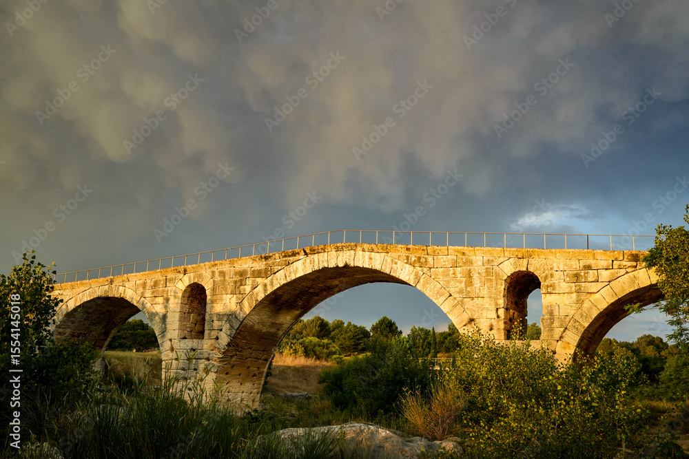 Fototapeta premium The famous Roman bridge Pont Julien in Bonnieux, Luberon, France. Atmospheric evening scene with a cloudy sky