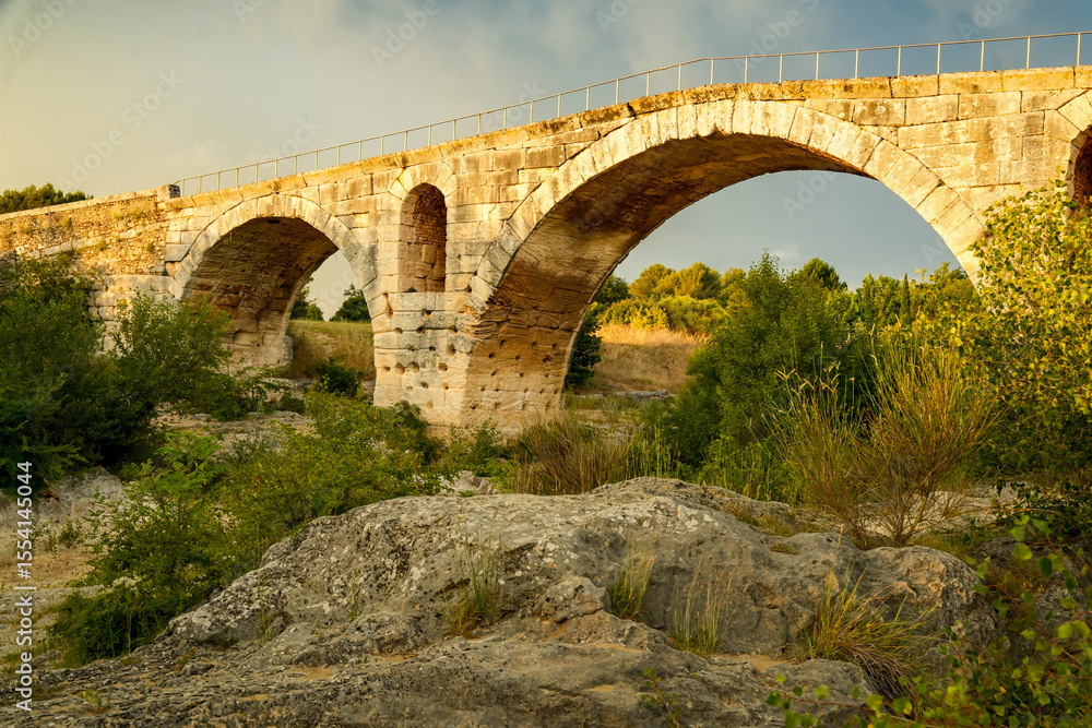 The famous Roman bridge Pont Julien in Bonnieux, Luberon, France. Atmospheric evening scene with a cloudy sky The famous Roman bridge Pont Julien in Bonnieux, Luberon, France. Atmospheric evening scene with a cloudy sky