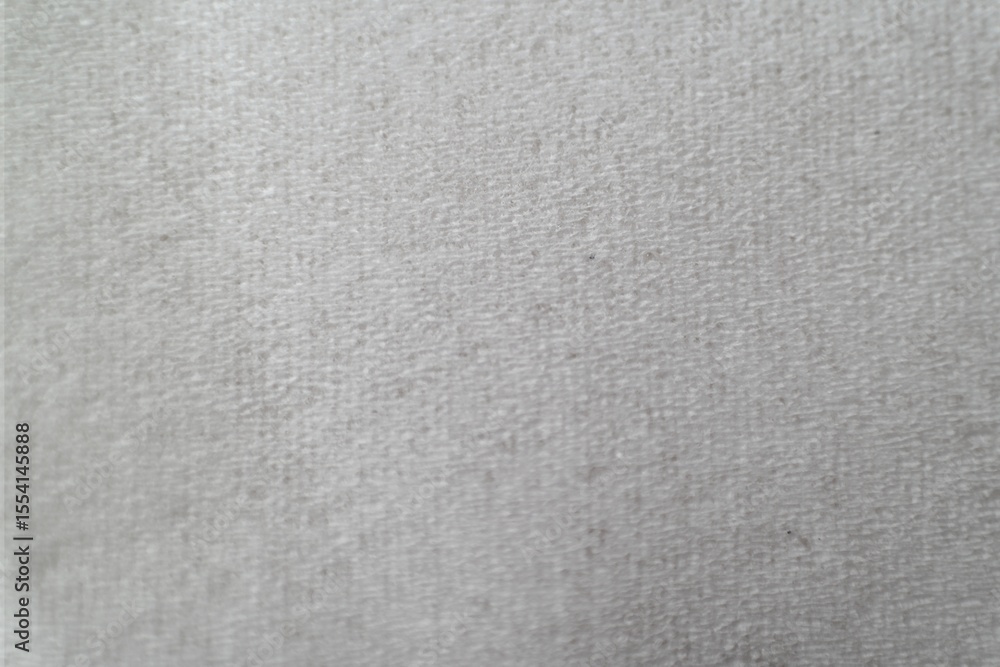 Fototapeta premium Close-up of a white textured fabric surface, featuring fine, subtle patterns. The image showcases a clean, minimalistic design with soft tactile qualities, ideal for backgrounds.