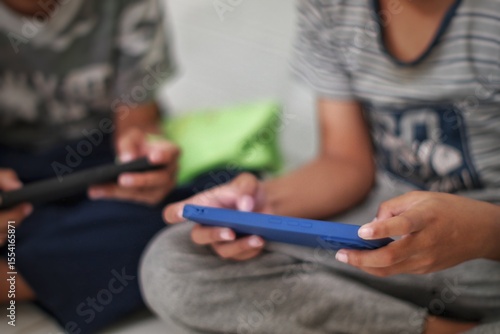 Fotografija Two Boys Engrossed in Mobile Devices A Study in Modern Childhood and Technology