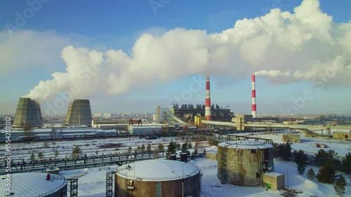 Wallpaper Mural A large industrial area features towering smoke stacks releasing white clouds into a clear blue sky. Snow blankets the ground, highlighting the contrast of industry and nature in winter. Torontodigital.ca
