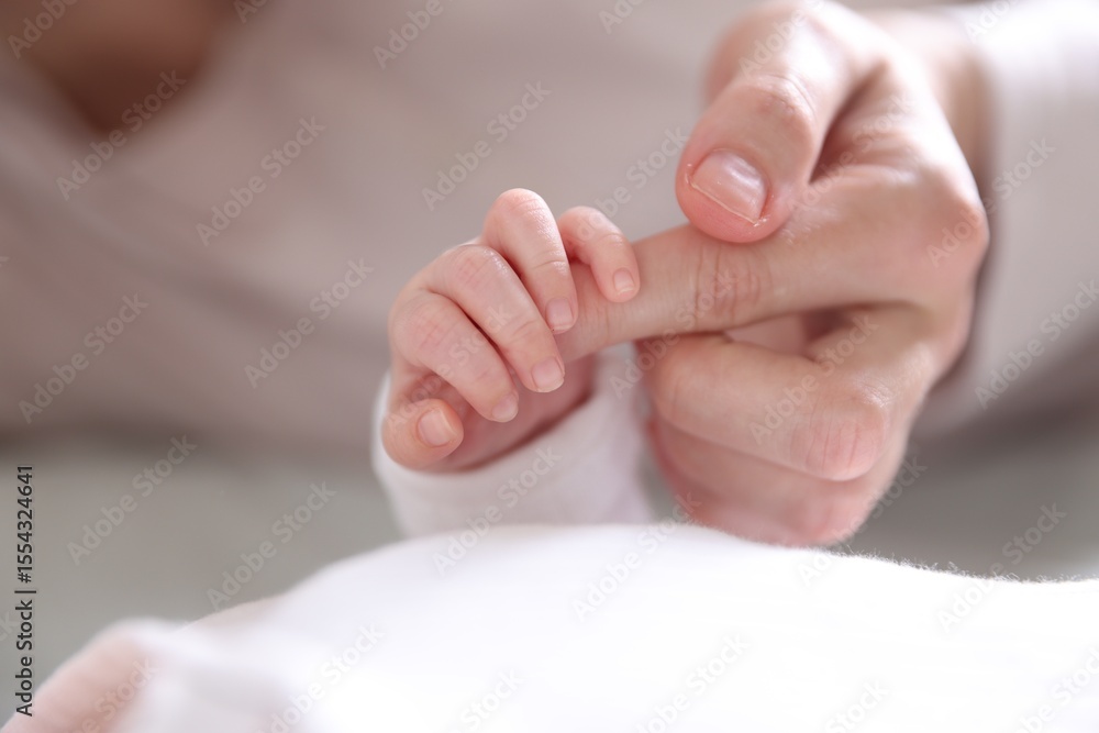 Mother holding her baby's hand indoors, closeup Mother holding her baby's hand indoors, closeup