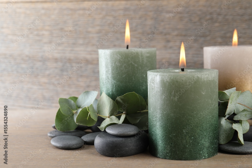 Burning candles, stones and eucalyptus branches on wooden table, closeup Burning candles, stones and eucalyptus branches on wooden table, closeup