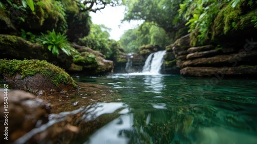 A peaceful and scenic waterfall flows into a crystal-clear pool, surrounded by lush greenery, portraying the calming beauty of nature and the serenity it offers.