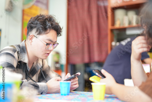 Photography Two Chinese men in their early twenties, both wearing glasses, are casually waiting at a Thai restaurant for their meal to be prepared on a pleasant spring day in Huangpu District, Shanghai, China
