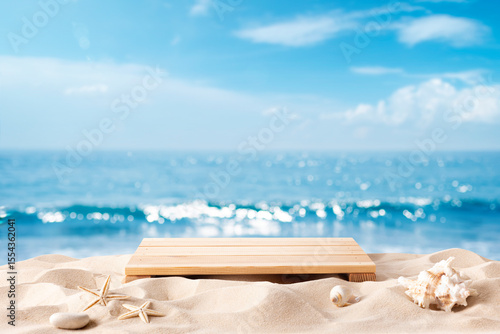 Podium with tropical shells on sandy beach for product presentation over blurred summer sea background
