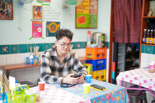 Canvas Print Two Chinese men in their early twenties, both wearing glasses, are casually waiting at a Thai restaurant for their meal to be prepared on a pleasant spring day in Huangpu District, Shanghai, China