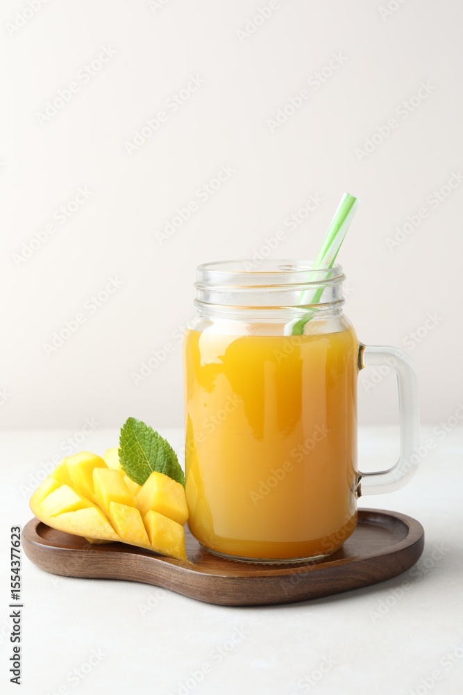 Fototapeta premium Tasty mango juice in glass mason jar, fresh fruit and mint on white table