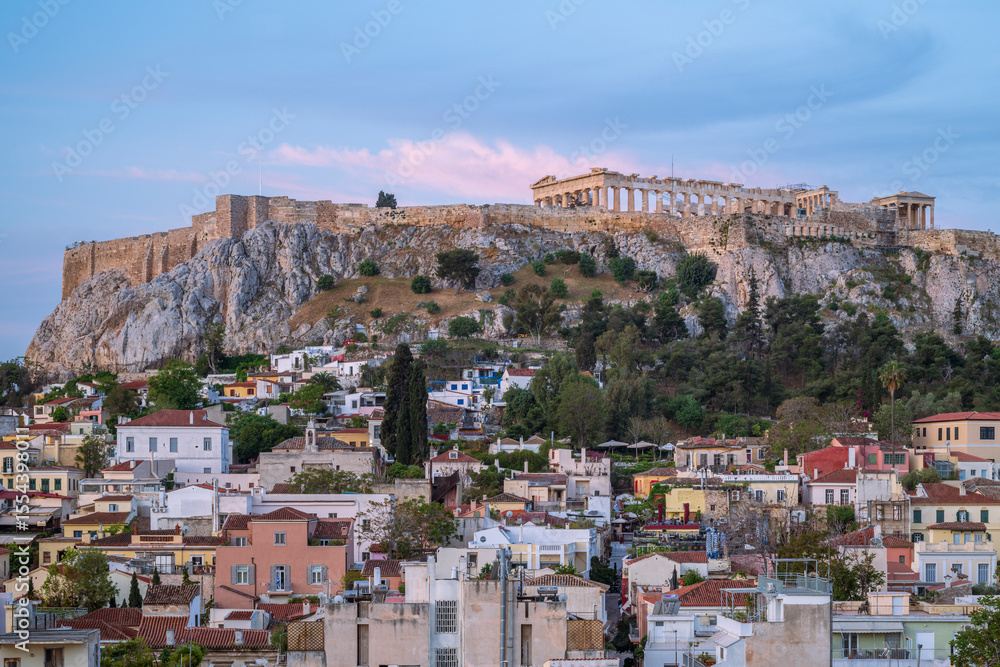 Obraz premium View of the Acropolis, in Athens, overlooking the old city, as the pink glow of early morning light illuminates the buildings and the Parthenon 
