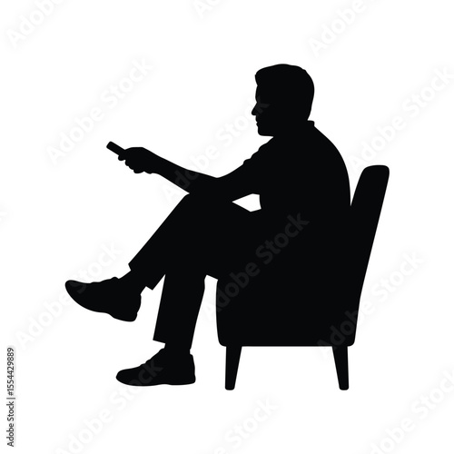 Silhouette of a man relaxing in an armchair with a remote