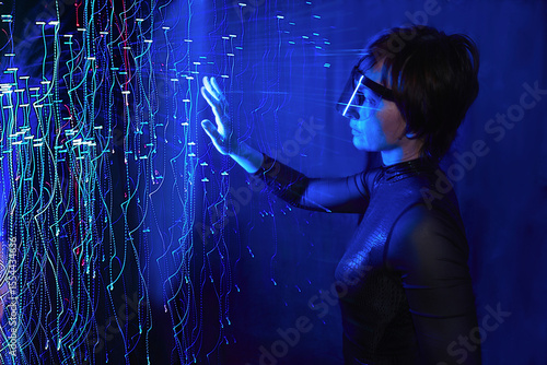 Woman using cyber glasses in a virtual reality simulator with neon lights