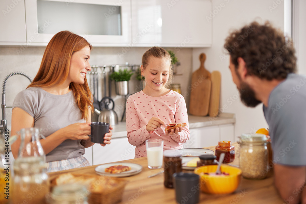 In a bright kitchen, a woman and a girl share a joyful moment over breakfast, while a man engages with them, creating a warm, family atmosphere of love and connection. In a bright kitchen, a woman and a girl share a joyful moment over breakfast, while a man engages with them, creating a warm, family atmosphere of love and connection.