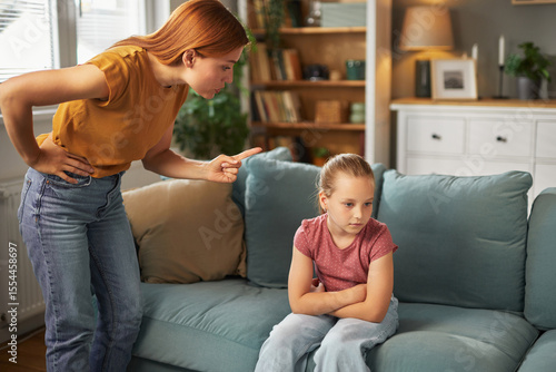 Obraz na plátně A mother is reprimanding her young daughter in a comfortable living room setting