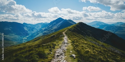 A scenic mountain ridge with a rocky trail under a blue sky filled with fluffy clouds.