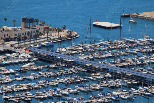 Alicante Marina with Solar Panel Dock, Moored Yachts, Palm-Lined Waterfront, and Modern Harbor Facilities under Clear Blue Sky
