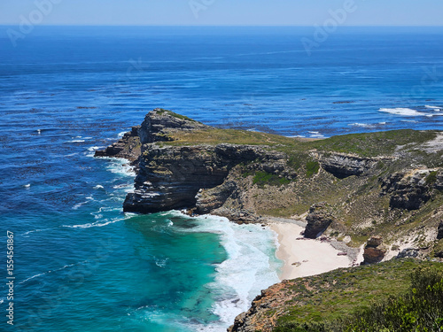 Beautiful beach with a rocky shoreline and a body of water. The water is a deep blue color, and the shoreline is lined with rocks that create a picturesque scene in Cape of good hope in South Africa
