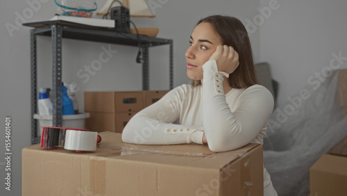 Obraz na plátně Woman smiling near packed boxes in new home interior, reflecting excitement and anticipation during moving process