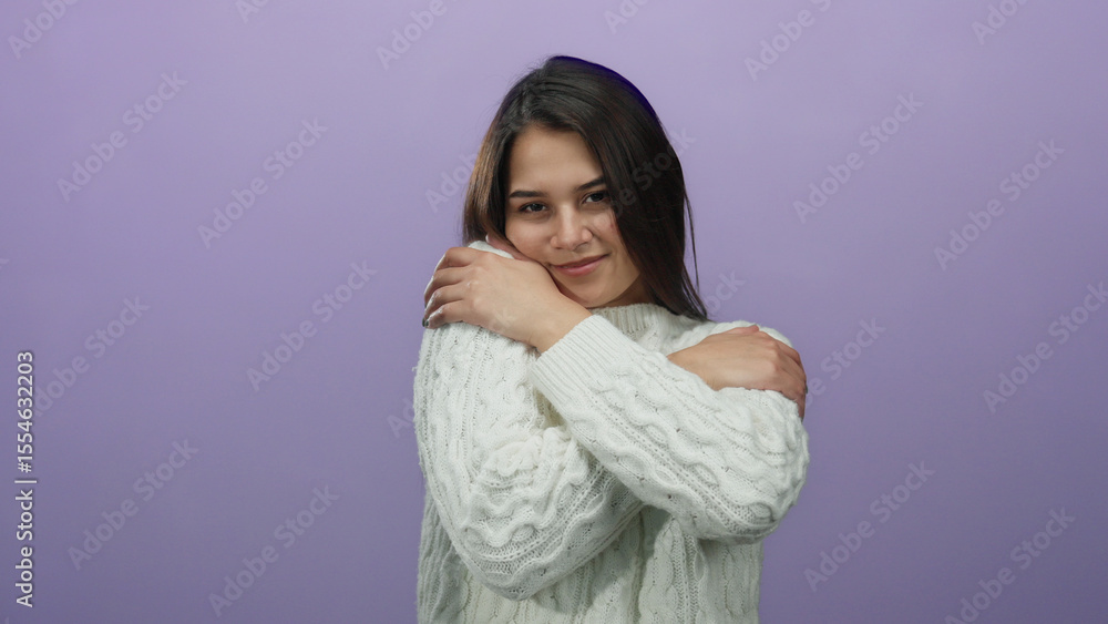 Woman smiling warmly in cozy white sweater embracing herself against vibrant purple backdrop enhancing feelings of warmth and comfort. Woman smiling warmly in cozy white sweater embracing herself against vibrant purple backdrop enhancing feelings of warmth and comfort.