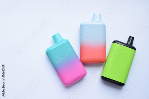 Several multi-colored electronic cigarettes lie on a light table.