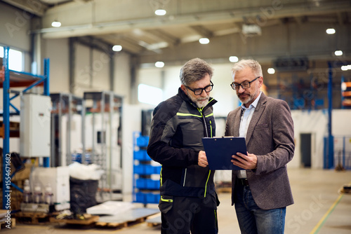 Two Professionals Reviewing a Document Together Inside a Modern Industrial Facility