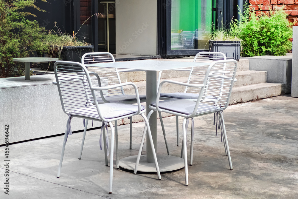 Fototapeta premium Modern outdoor seating area with metal chairs and table in a contemporary space