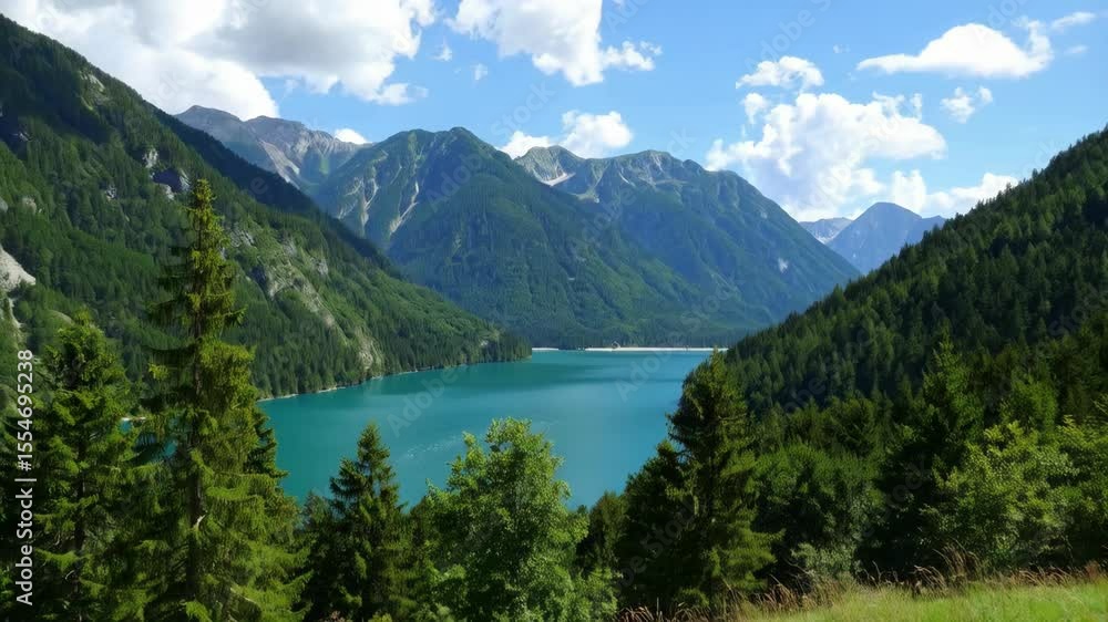 Scenic mountain lake surrounded by forest and peaks under a blue sky with fluffy clouds Scenic mountain lake surrounded by forest and peaks under a blue sky with fluffy clouds