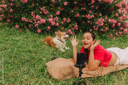 Young girl with Corgi recording video on phone share via app her travel vacation. Gen Z influencer shooting social media stories. Concept of friendship between a dog and human. Part of a series. UGC