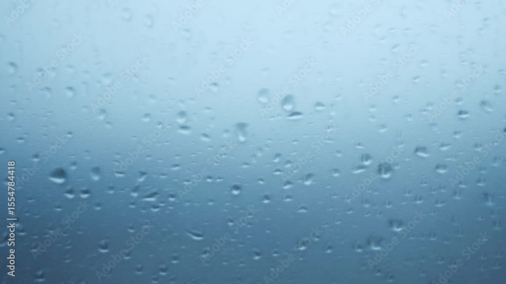 Water raindrops falling on the frosted glass outside the window. Atmospheric rain scene use for background in video projects. Feelings of calm. Water raindrops falling on the frosted glass outside the window. Atmospheric rain scene use for background in video projects. Feelings of calm.