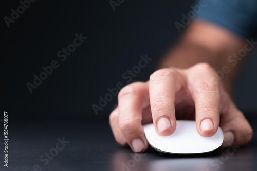 Bilde på lerret Close-up of a hand clicking a white wireless mouse on a dark background